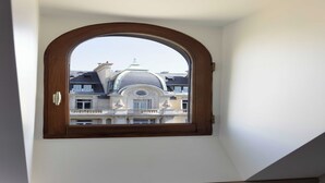 Una habitación con ventanal de madera que da a un edificio de arquitectura clásica.