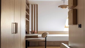 Una habitación pequeña con cama, escritorio, silla y armario.