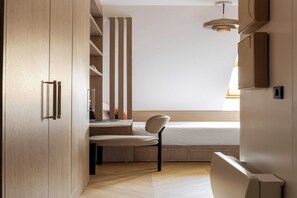 Ein kleines Zimmer mit einem Bett, einem Schreibtisch, einem Stuhl und einem Kleiderschrank.