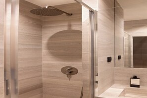 Ein modernes Badezimmer mit Duschkabine aus Glas, Marmorwand und einer kleinen Spüle.
