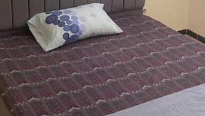 A bed with a patterned bedspread, a pillow with a blue and white design, and a folded blanket.