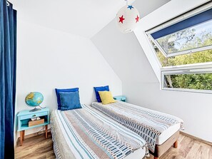 Un dormitorio con dos camas, un globo en una mesita de noche, una ventana con vistas a árboles y una lámpara colgante con diseño de estrellas.