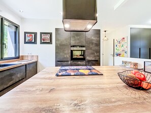A modern kitchen with a wooden countertop, a built-in oven, and a large window. - Maison de Kermamas by Interhome (Sarzeau)