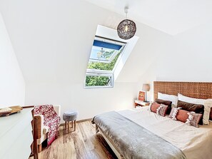 A bedroom with a skylight, a bed with multiple pillows, a bedside table with a lamp, and a small stool. - Maison de Kermamas by Interhome (Sarzeau)