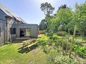 A wooden building with a patio, a table with chairs, and a garden with various plants. - Maison de Kermamas by Interhome (Sarzeau)