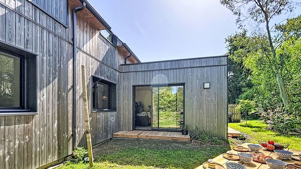 A modern wooden house with a patio, a sliding glass door, and a table with patterned bowls. - Maison de Kermamas by Interhome (Sarzeau)