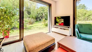 A modern living room with a large TV, a green sofa, and a wooden bench. - Maison de Kermamas by Interhome (Sarzeau)