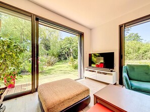 A modern living room with a large TV, a green sofa, and a wooden bench. - Maison de Kermamas by Interhome (Sarzeau)