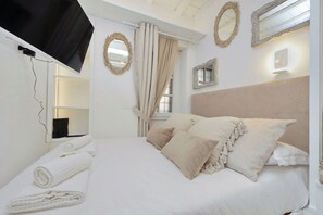 A hotel room with a bed, curtains, a mirror, and a TV mounted on the wall. - Apartment in Rome with 0 bedrooms sleeps 2 (Rome)