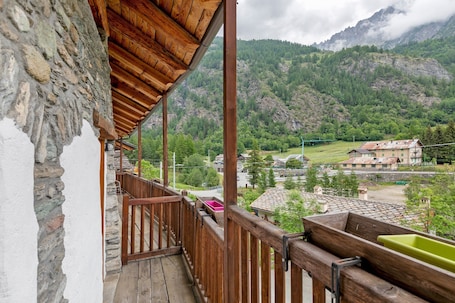 A balcony with a stone wall, wooden railing, and a view of a mountainous landscape.. Room 'Camera 1 - Tripla' with Mountain View, Balcony and Wi-Fi