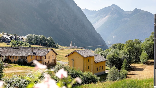 Un pueblo rural con casas tradicionales, una iglesia y montañas al fondo.