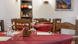 Una mesa de comedor con mantel rojo, un reloj de madera con forma de corazón y una copa de vino.