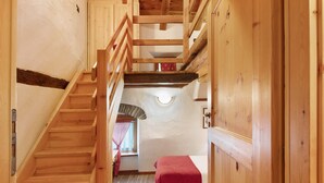Eine Holztreppe führt zu einem Zimmer mit Bett und Fenster.