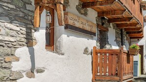 Ein rustikales Gebäude mit einem Holzschild, auf dem 'Locanda delle Miniere' steht, und einer Steinmauer.