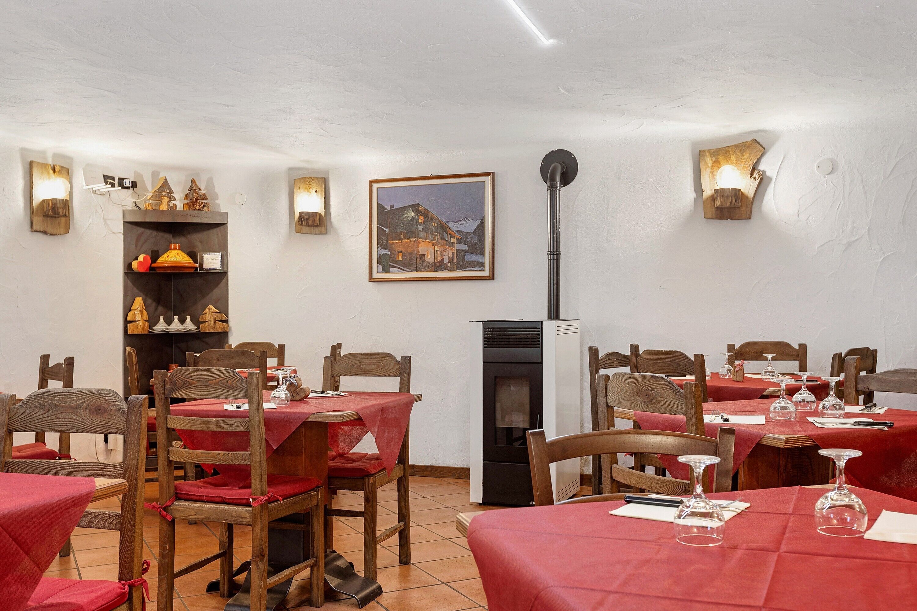 Un espace repas avec des chaises et des tables en bois, une cheminée et des lampes fixées au mur.