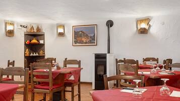 Un espace repas avec des chaises et des tables en bois, une cheminée et des lampes fixées au mur.