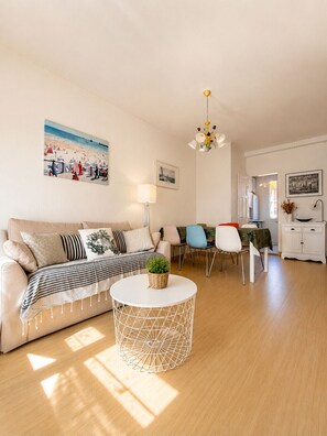 Ein Wohnzimmer mit einer Couch, einem runden Couchtisch und einem Essbereich mit Stühlen und einem Tisch.