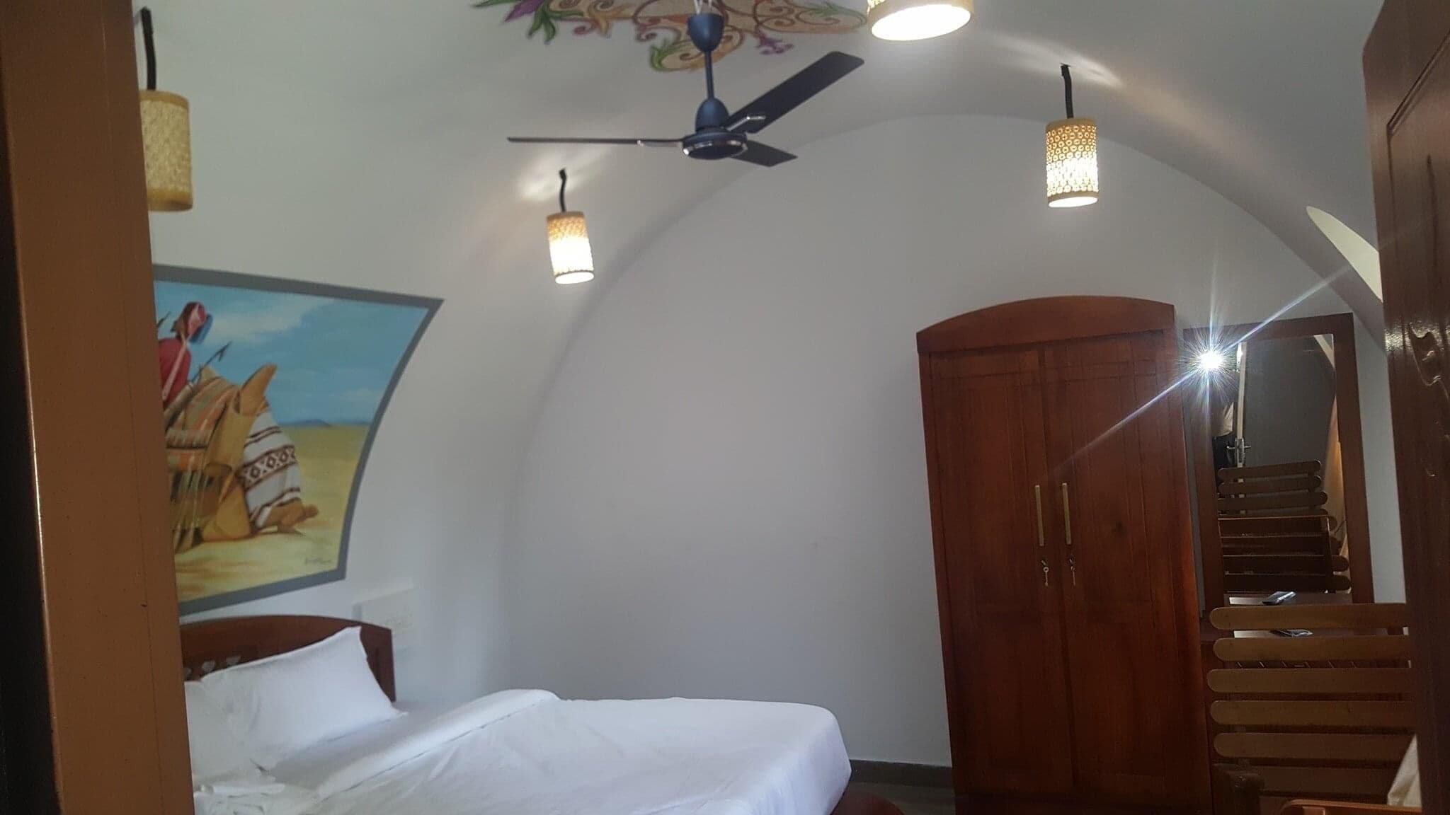 Une chambre à coucher avec un lit, un ventilateur de plafond et une armoire en bois.