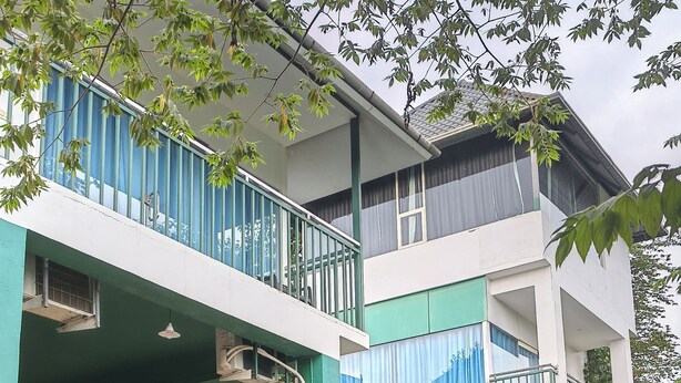 A multi-story building with balconies, stone structures with arches, and a green and white color scheme. - Wayanad Cave N Pillar Resort (Krishnagiri)