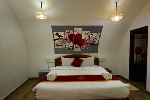 Une chambre d’hôtel avec un lit, deux lampes suspendues, une œuvre d’art murale et un plancher en bois.