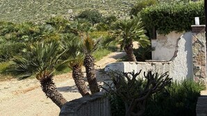 Paisaje montañoso con vegetación escasa y un edificio de fachada de piedra.