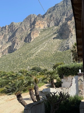 A mountainous landscape with sparse vegetation and a building with a stone facade.