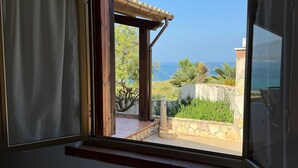 Una habitación con ventana que da a un patio con vista al mar.