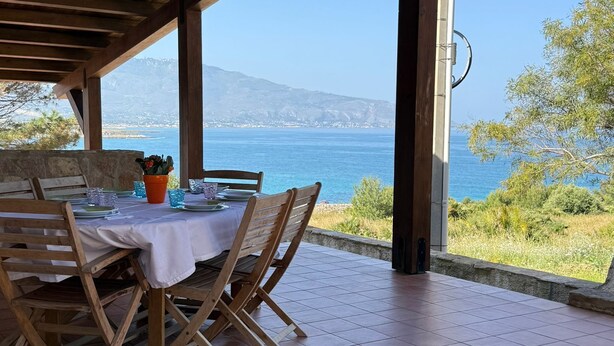 Un espacio para comer al aire libre con vista al mar y una montaña al fondo.