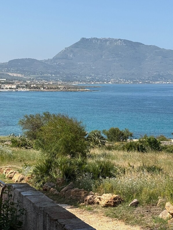 Un paysage côtier avec une montagne en arrière-plan, un ciel dégagé et une vue sur la mer.