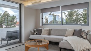A modern living room with a sofa, a glass coffee table, and a view through large windows. - Sea View Riviera Maisonette with Large Terraces (Voula)