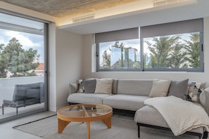 Ein stilvolles Wohnzimmer mit einer Couch, einem Glastisch und Blick durch große Fenster.