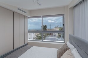 Ein Schlafzimmer mit großem Fenster, einem Bett und einem Kleiderschrank.