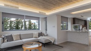 A modern living room with a sofa, coffee table, and large windows. - Sea View Riviera Maisonette with Large Terraces (Voula)
