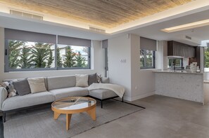 Ein modernes Wohnzimmer mit Sofa, Couchtisch und großen Fenstern.