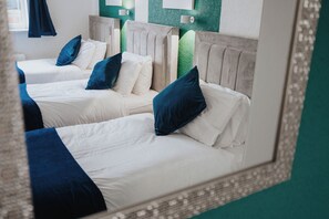 A hotel room with two beds, each with a headboard, pillows, and a framed picture.