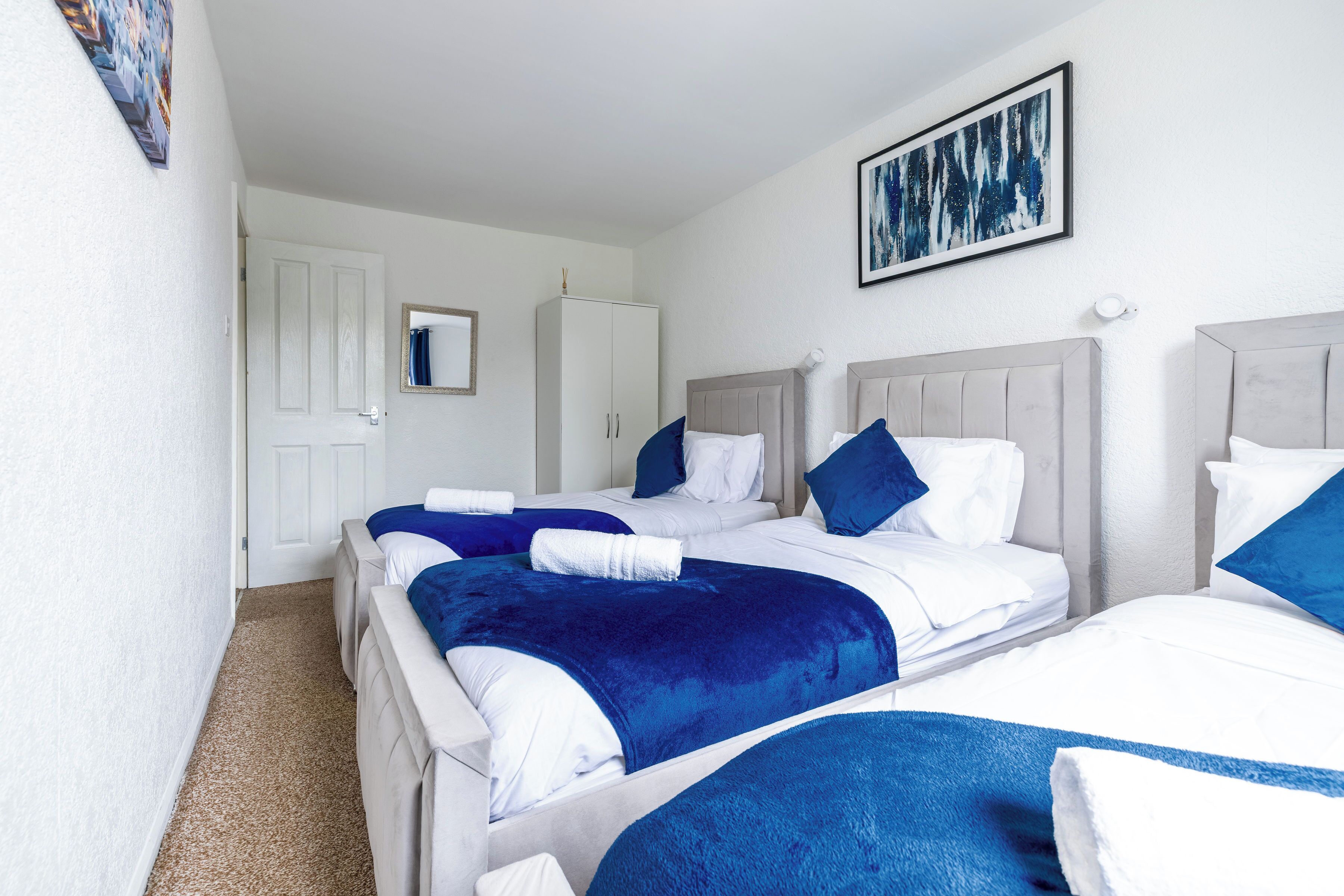 Een hotelkamer met twee bedden, een kast, een spiegel en een schilderij aan de muur.