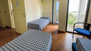A room with two beds, a chair, a radiator, and a balcony with a view. - Vacation home Vidal by Interhome (Spoltore)