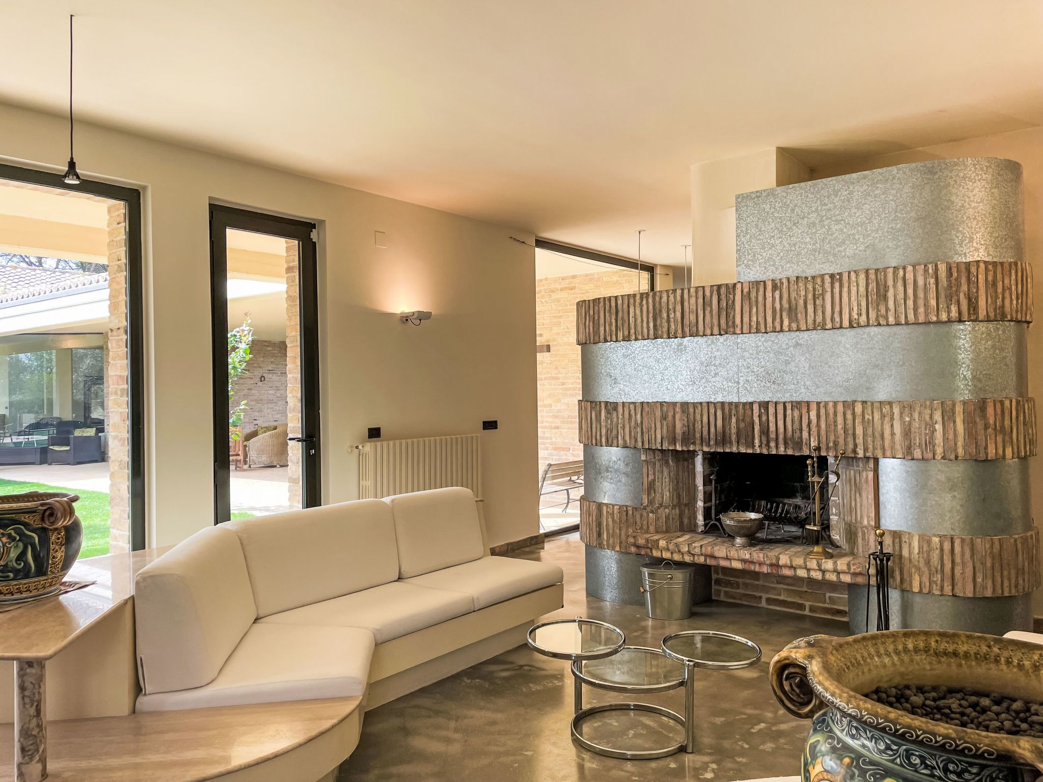 Uma sala de estar moderna com um sofá branco, uma lareira e uma mesa de centro de vidro.