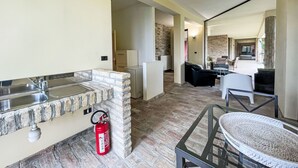 A modern kitchen with a stone backsplash, a fire extinguisher, and a glass-top table. - Vacation home Vidal by Interhome (Spoltore)