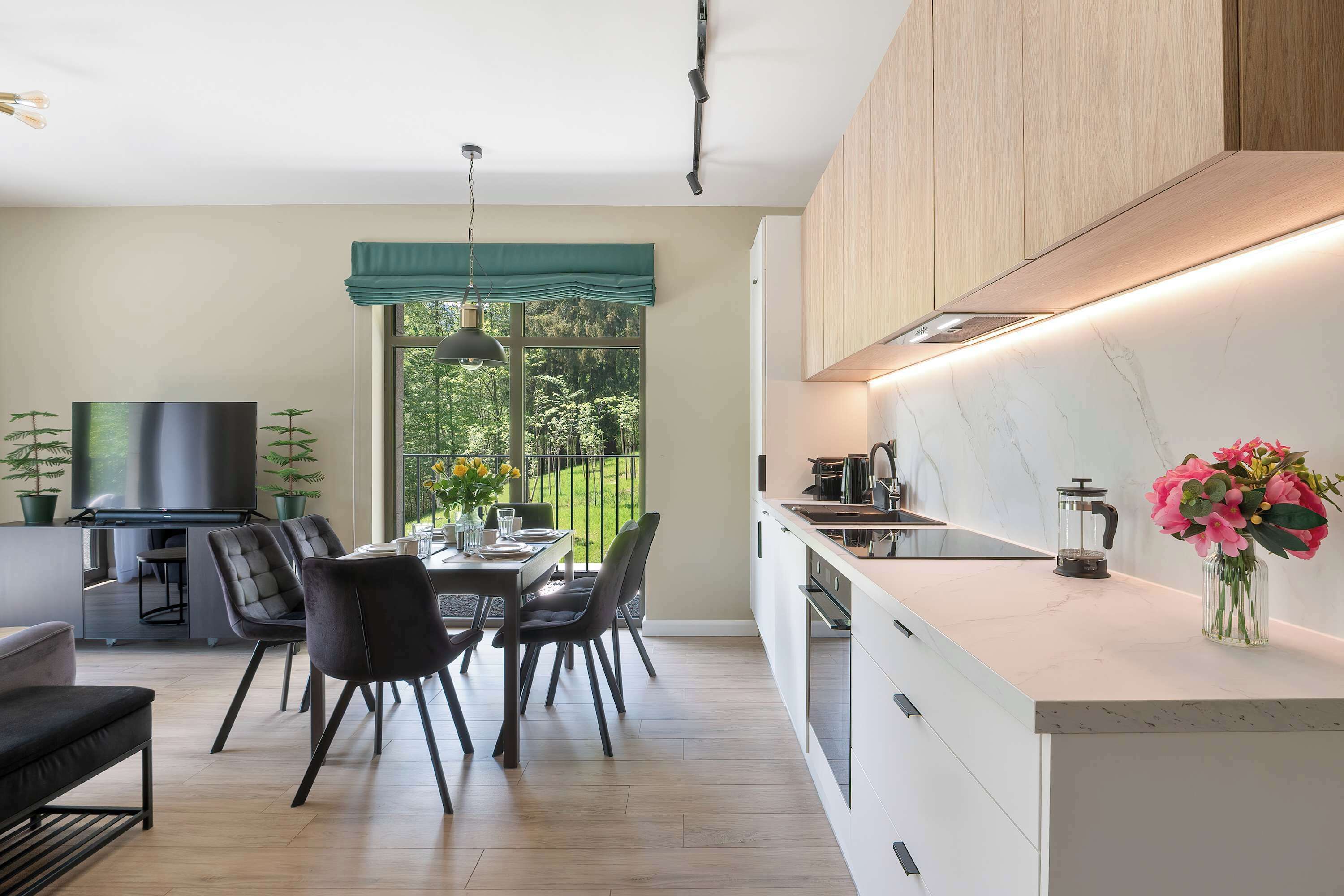 Une cuisine moderne avec un coin repas, des meubles en bois et une grande fenêtre.