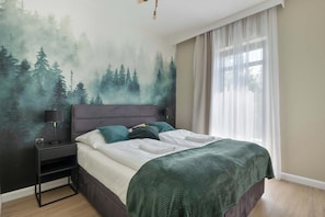 Une chambre à coucher avec un lit, une table de chevet et une fresque murale représentant une forêt.