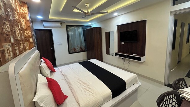 A modern bedroom with a bed, a ceiling fan, recessed lighting, a TV, and a wardrobe. - Hotel Venus Inn (Indore)