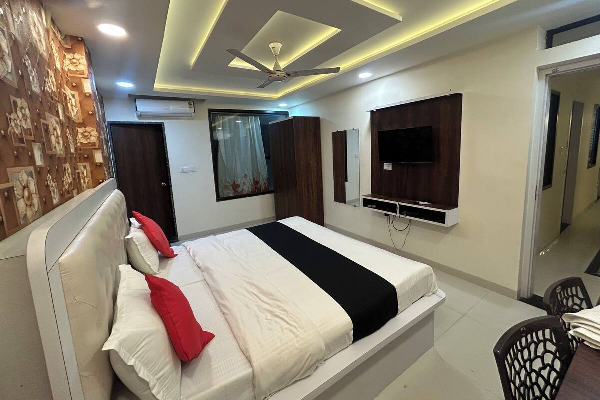 A modern bedroom with a bed, a ceiling fan, recessed lighting, a TV, and a wardrobe.
