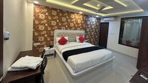 A bedroom with a bed, bedside table, and a desk. - Hotel Venus Inn (Indore)