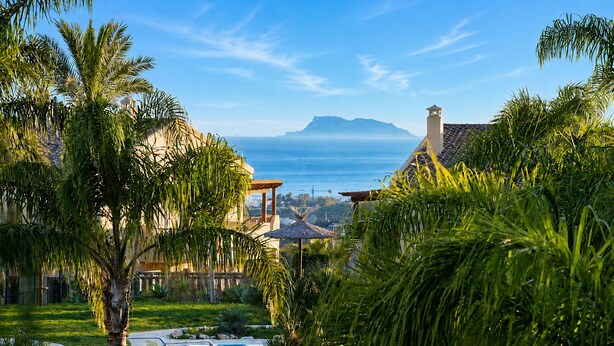 Ein Resort mit Pool, Palmen und Blick auf das Meer und die Berge.