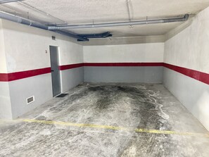 Eine saubere, leere Garage mit weiĂen WĂ€nden und roten Streifen, einer TĂŒr und einem LĂŒftungsgitter.