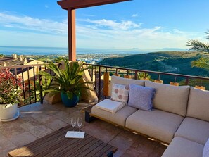 Ein Balkon mit einer Couch, einem Tisch und einem Blumentopf.