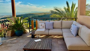 Ein Balkon mit einer Couch, einem Tisch und Topfpflanzen.