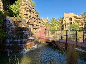 A waterfall, a bridge, and buildings in the background.