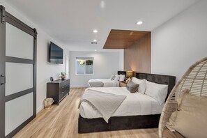 Ein modernes Schlafzimmer mit einem großen Bett, einem Fernseher und einer Holzbodenverkleidung.